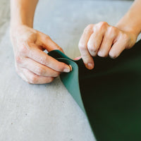 Green foldable repotting mat laid flat with plant and soil on top for mess-free repotting