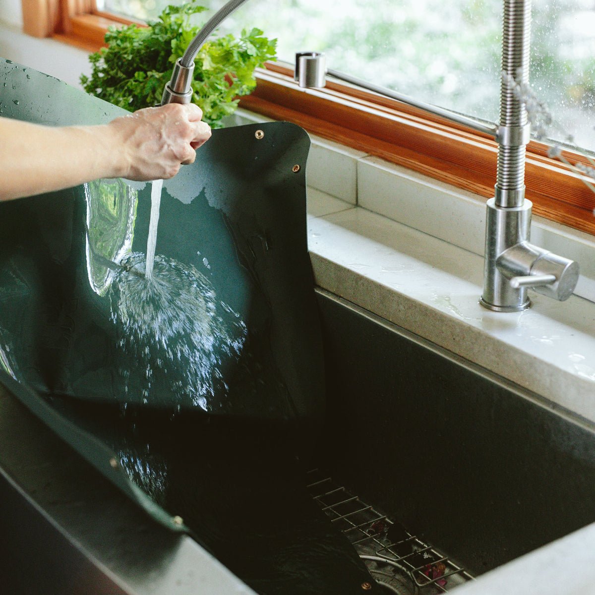 Green foldable repotting mat laid flat with plant and soil on top for mess-free repotting